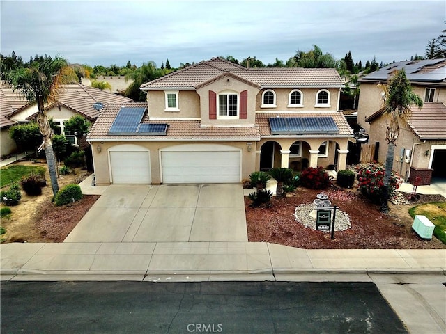2653 Ashcroft Ave, Clovis, CA 93611 - mediterranean / spanish house with stucco siding, a tiled roof, roof mounted solar panels, concrete driveway, and an attached garage