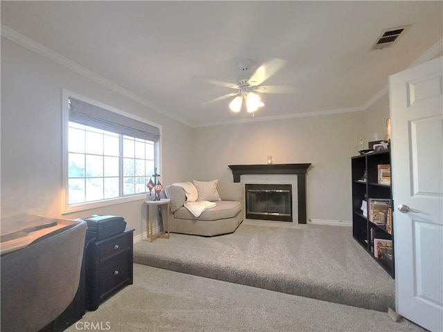 carpeted living area featuring visible vents, ceiling fan, baseboards, a glass covered fireplace, and ornamental molding