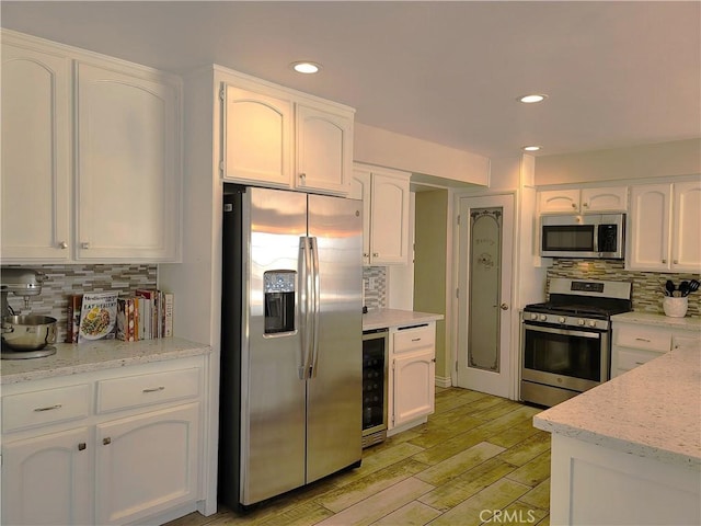 kitchen with white cabinets, backsplash, stainless steel appliances, and beverage cooler