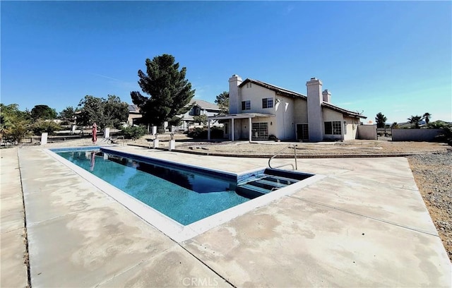 outdoor pool with fence and a patio area