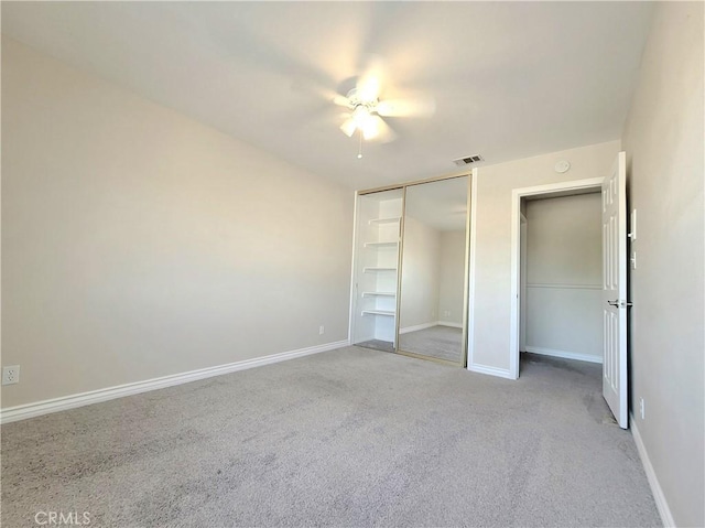 unfurnished bedroom featuring light colored carpet, a closet, ceiling fan, baseboards, and visible vents