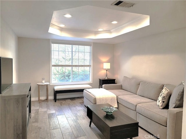 living area with recessed lighting, light wood-type flooring, baseboards, visible vents, and a tray ceiling