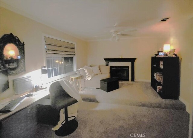living area featuring visible vents, ceiling fan, carpet floors, and a glass covered fireplace