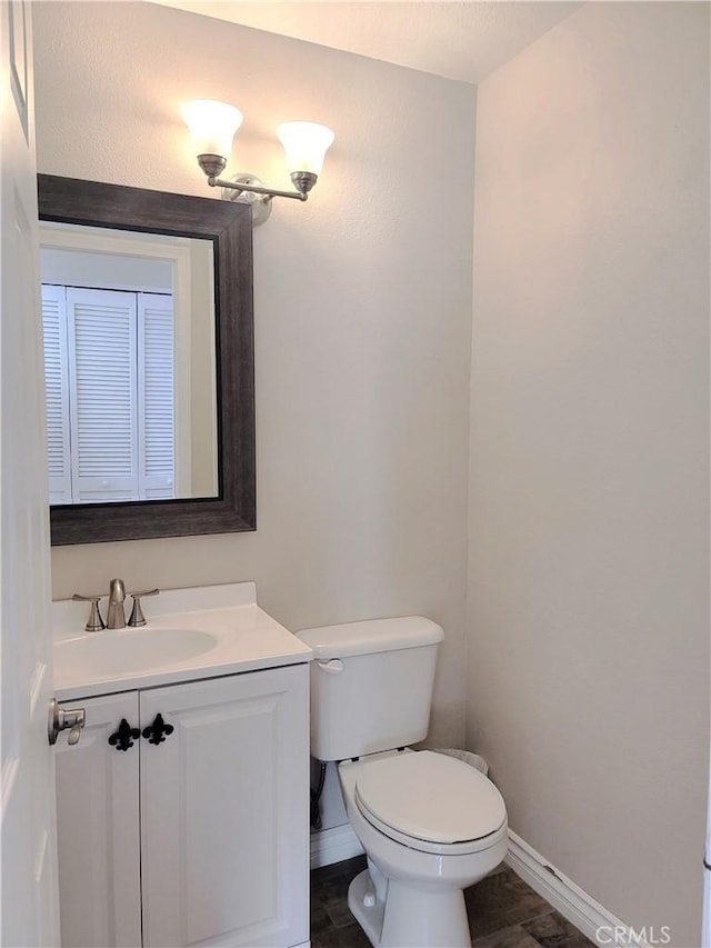 bathroom with toilet, vanity, and baseboards