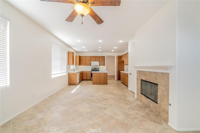 36877 Meadow Brook Way, Beaumont, CA 92223 - kitchen featuring white microwave, a ceiling fan, a fireplace, light countertops, and brown cabinetry