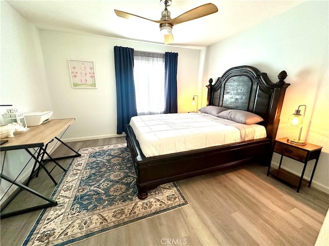 bedroom with wood finished floors, a ceiling fan, and baseboards