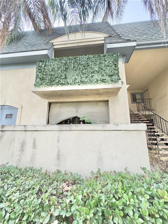 view of side of home with stucco siding, an attached garage, and stairway