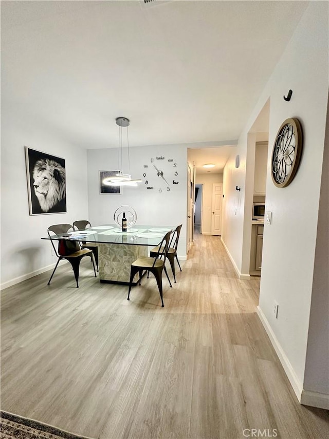 dining space featuring baseboards and light wood-style flooring