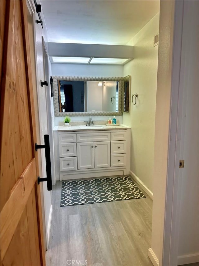 bathroom featuring baseboards, wood finished floors, visible vents, and vanity
