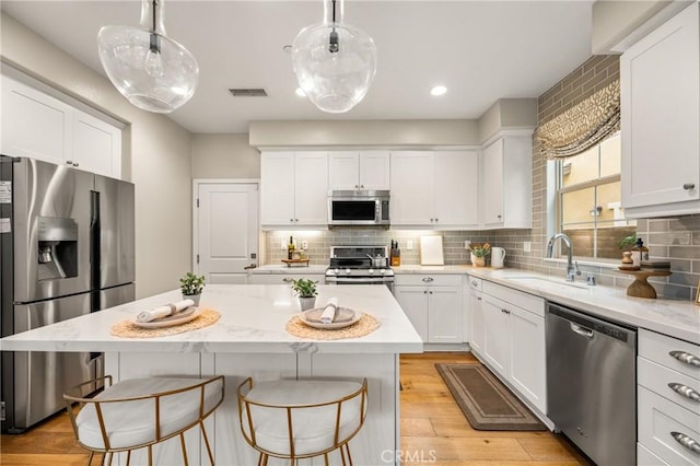 109 Baculo St, Rancho Mission Viejo, CA 92694 - kitchen featuring stainless steel appliances, a sink, visible vents, a kitchen bar, and white cabinetry