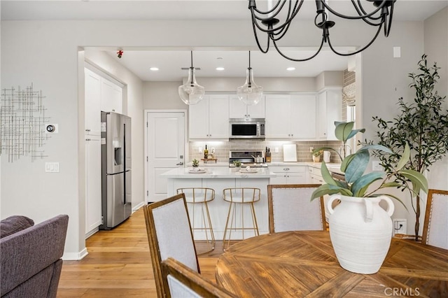 109 Baculo St, Rancho Mission Viejo, CA 92694 - kitchen with stainless steel appliances, tasteful backsplash, white cabinetry, light countertops, and hanging light fixtures