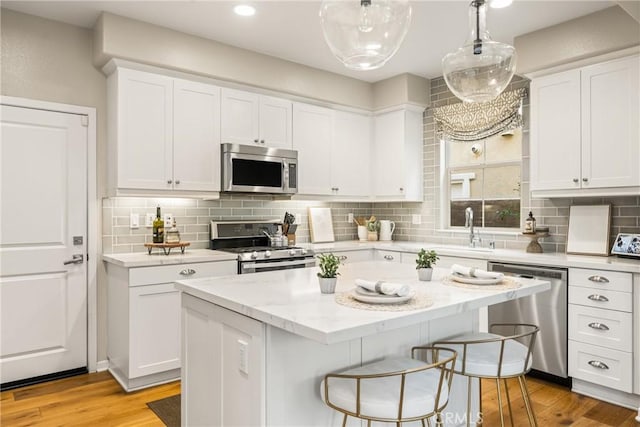109 Baculo St, Rancho Mission Viejo, CA 92694 - kitchen with white cabinets, light wood-type flooring, appliances with stainless steel finishes, and a breakfast bar area