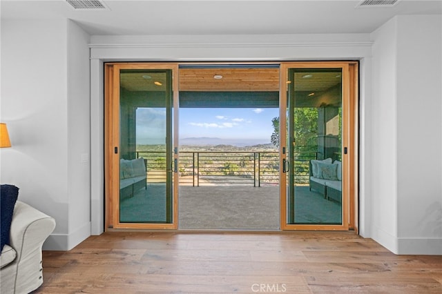 doorway to outside with visible vents, baseboards, and wood finished floors