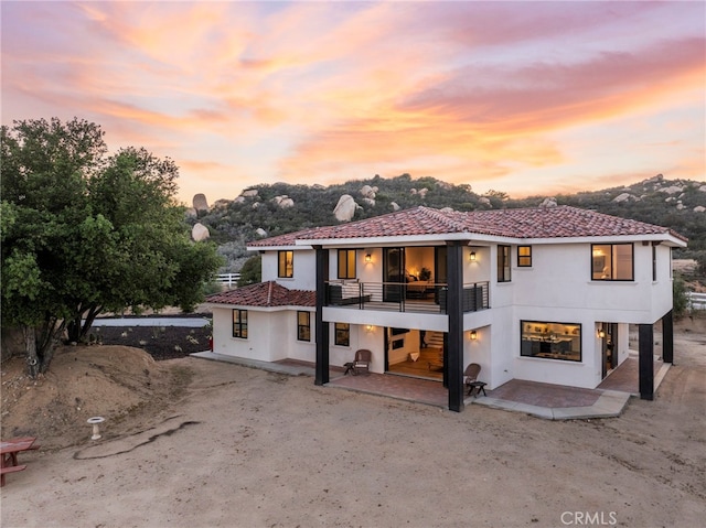 back of property featuring a balcony, a patio area, and stucco siding