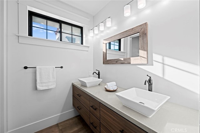 full bathroom featuring double vanity, baseboards, and a sink