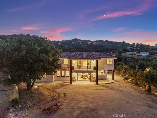 view of front of house featuring a patio area, stucco siding, a tiled roof, and a balcony