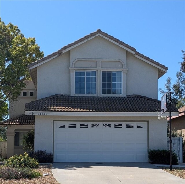 traditional-style house with an attached garage, a tile roof, and driveway