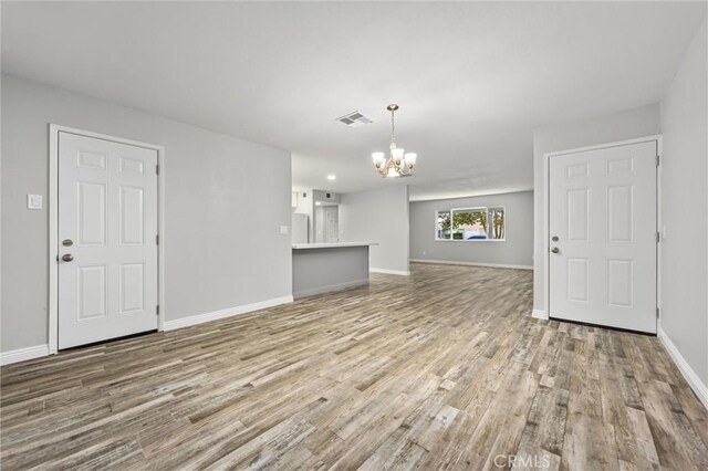 513 River Oaks Dr, Bakersfield, CA 93309 - unfurnished living room with an inviting chandelier, wood finished floors, visible vents, and baseboards