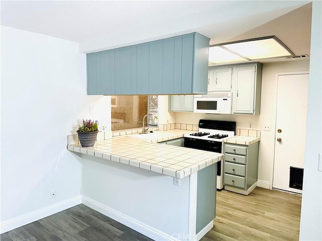 22703 Copper Hill Dr Unit 2, Saugus, CA 91350 - kitchen with gas range, baseboards, light wood finished floors, white microwave, and a peninsula