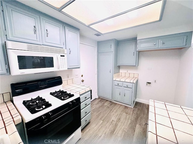 22703 Copper Hill Dr Unit 2, Saugus, CA 91350 - kitchen with tile counters, light wood-style floors, gas range, white microwave, and visible vents