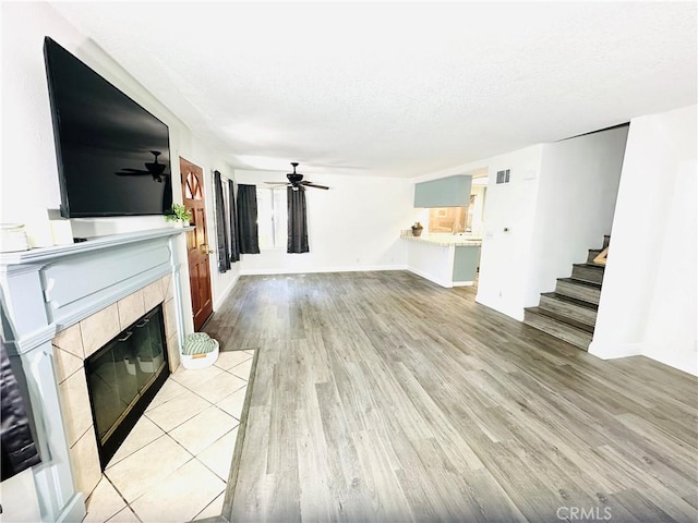 22703 Copper Hill Dr Unit 2, Saugus, CA 91350 - unfurnished living room featuring stairway, visible vents, a ceiling fan, light wood-style floors, and a tiled fireplace