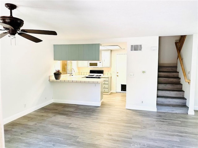 22703 Copper Hill Dr Unit 2, Saugus, CA 91350 - kitchen with a ceiling fan, tile countertops, white microwave, a peninsula, and visible vents