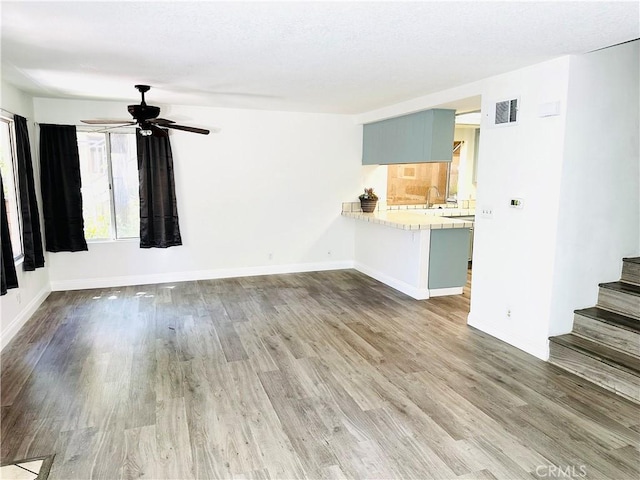 22703 Copper Hill Dr Unit 2, Saugus, CA 91350 - unfurnished living room with stairs, wood finished floors, ceiling fan, baseboards, and visible vents