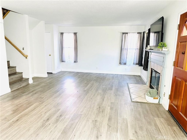 22703 Copper Hill Dr Unit 2, Saugus, CA 91350 - unfurnished living room with stairway, a fireplace, light wood-style floors, and plenty of natural light