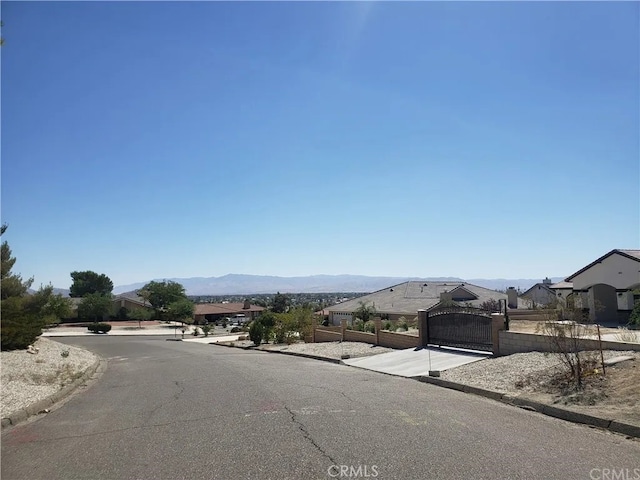 16389 Viho Ct, Apple Valley, CA 92307 - view of asphalt road featuring curbs, a mountain view, a gate, and a residential view