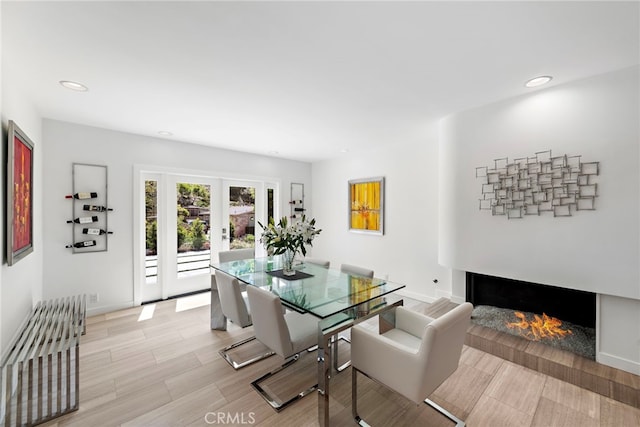 3120 Bern Dr, Laguna Beach, CA 92651 - dining space with recessed lighting, french doors, a warm lit fireplace, and light wood-style flooring
