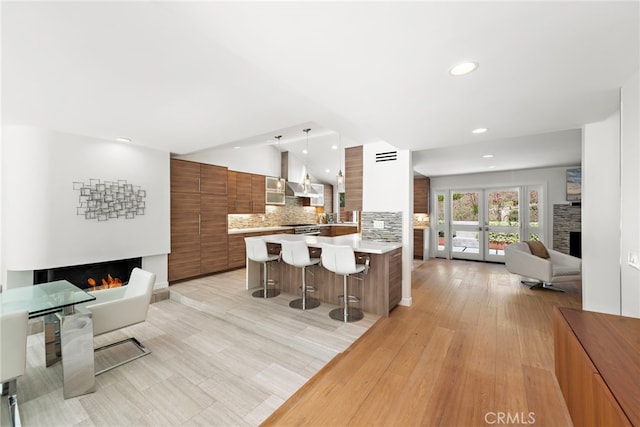 3120 Bern Dr, Laguna Beach, CA 92651 - kitchen featuring a lit fireplace, modern cabinets, a kitchen bar, open floor plan, and brown cabinets