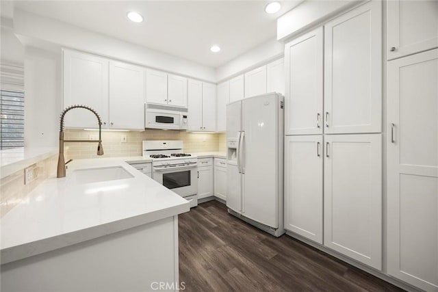 kitchen with white cabinets, a sink, dark wood-style flooring, white appliances, and light countertops