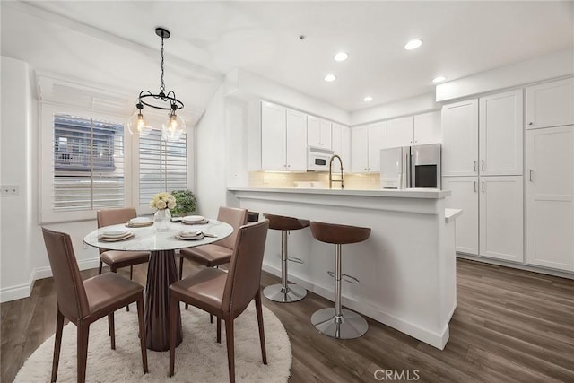 kitchen featuring refrigerator with ice dispenser, white microwave, dark wood-type flooring, and white cabinetry
