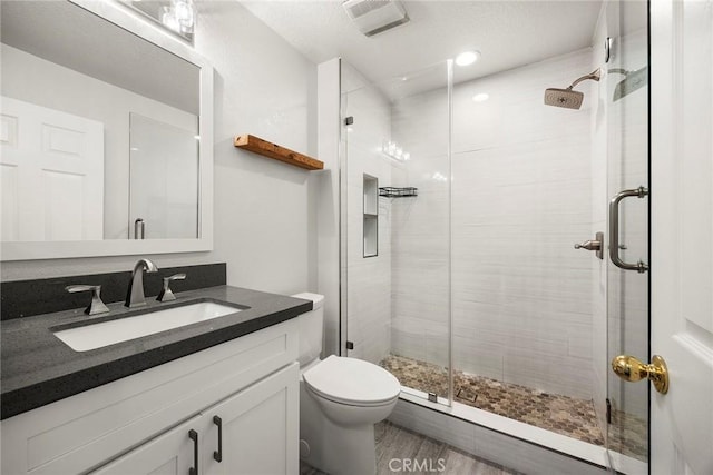 full bathroom with visible vents, vanity, a shower stall, and toilet