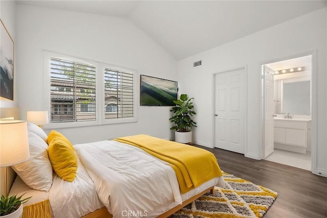bedroom featuring vaulted ceiling, visible vents, wood finished floors, connected bathroom, and a sink