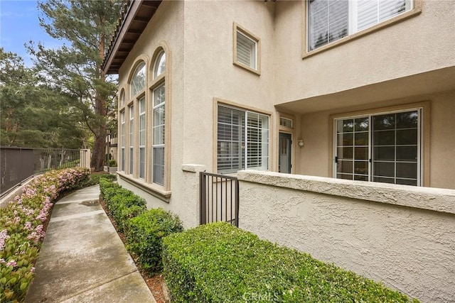 view of side of property featuring stucco siding and fence