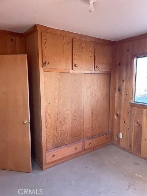 mudroom with unfinished concrete floors and wood walls