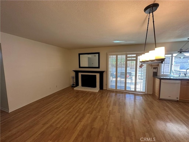 21643 Spice Ct, Saugus, CA 91350 - unfurnished living room featuring a textured ceiling, wood finished floors, a fireplace, and healthy amount of natural light