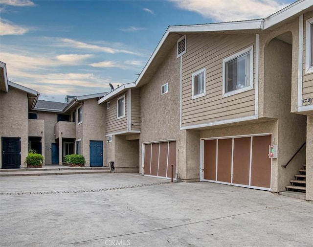 exterior space with stucco siding, driveway, and a garage