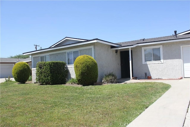 ranch-style house with an attached garage, a front lawn, and stucco siding