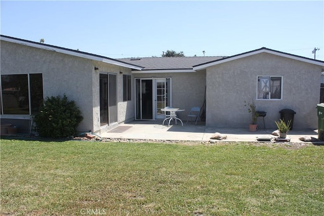 back of property featuring a yard, a patio area, and stucco siding