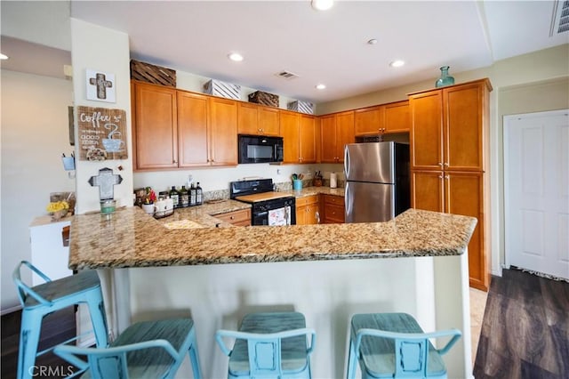 27518 Hazelhurst St Unit 1, Murrieta, CA 92562 - kitchen with black appliances, a peninsula, a breakfast bar area, light stone counters, and recessed lighting
