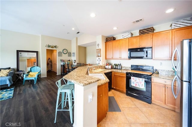 27518 Hazelhurst St Unit 1, Murrieta, CA 92562 - kitchen with black appliances, a peninsula, a sink, light stone countertops, and a breakfast bar