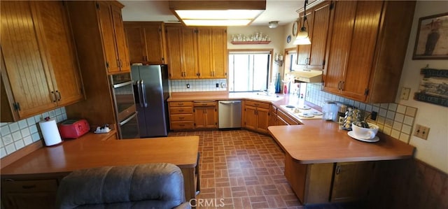 25205 5th Ave, Los Molinos, CA 96055 - kitchen featuring brick patterned floor, stainless steel dishwasher, freestanding refrigerator, tasteful backsplash, and brown cabinetry
