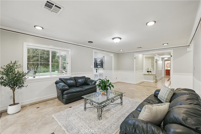 living area with a wainscoted wall, visible vents, recessed lighting, crown molding, and light tile patterned floors