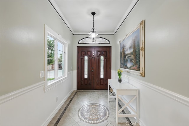 entrance foyer with an inviting chandelier, crown molding, and a wainscoted wall