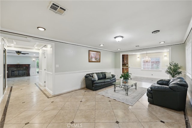 living area featuring wainscoting, visible vents, light tile patterned floors, and crown molding