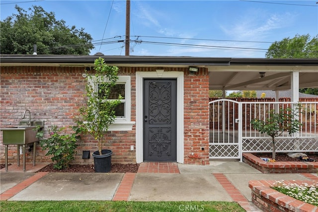 doorway to property featuring a gate and brick siding