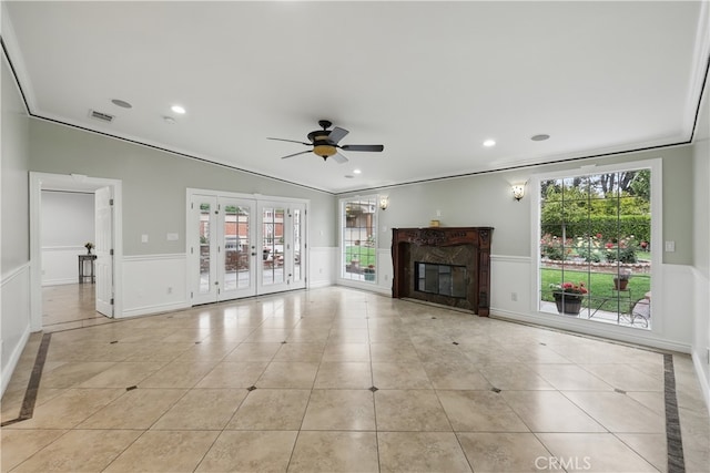 unfurnished living room with light tile patterned floors, a wainscoted wall, visible vents, and ceiling fan