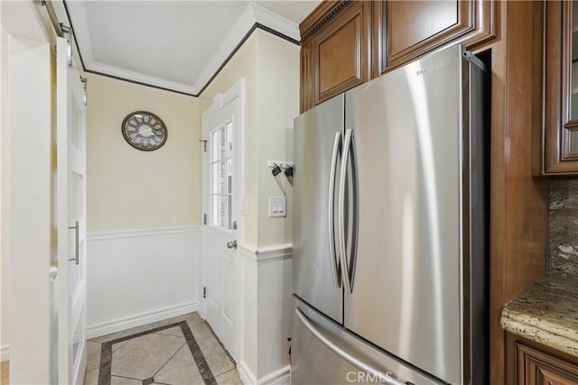 kitchen featuring crown molding, light stone countertops, and freestanding refrigerator